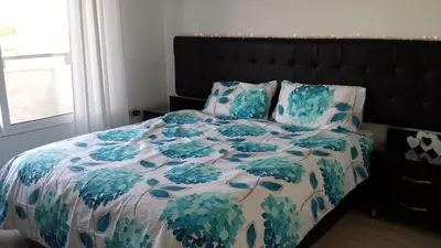 a bed with a blue and white blanket and pillows at The Place Apartments in Amman