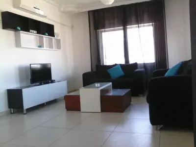 a living room with a couch and a tv at The Place Apartments in Amman