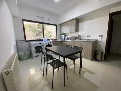 a kitchen with a table and two chairs and a washing machine at Lemon Tree Residence in Amman