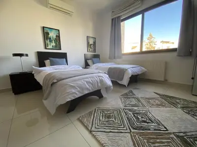 a bedroom with two beds and a large window at Lemon Tree Residence in Amman