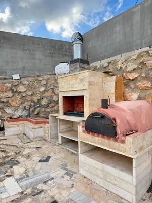 an outdoor pizza oven with a brick wall at Abu Hossam s chalet in Jerash