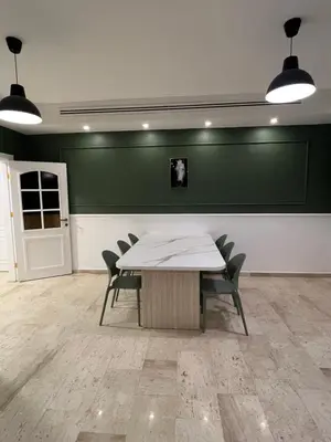 a table and chairs in a room with a green wall at bedroom (3) apartment of 200 square meters with an outdoor terrace in Umm Uthainah