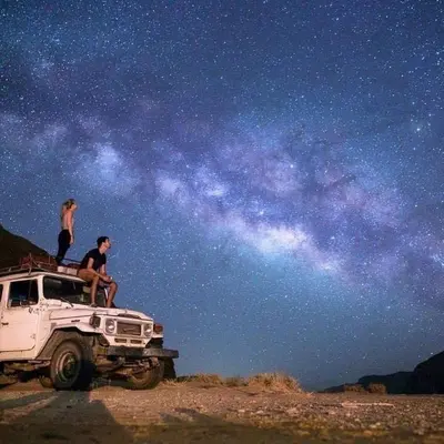a man and a woman sitting on the roof of a truck at Wadi Rum Desert Heart Camp in Wadi Rum