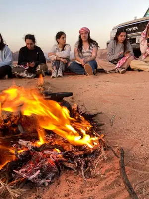 a group of people sitting around a fire on the beach at Wadi Rum Desert Heart Camp in Wadi Rum
