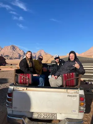 a group of people sitting in the back of a truck at Jawharat Rum camp in Wadi Rum