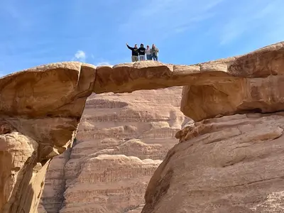 three people standing on a bridge over a canyon at Jawharat Rum camp in Wadi Rum