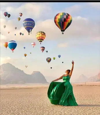 a woman in a green dress standing in front of balloons at The sunset of Wadi Rum in Wadi Rum