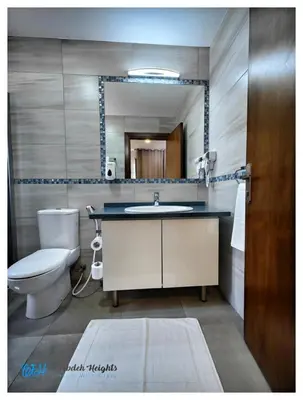 a bathroom with a sink and a toilet and a mirror at Weibdeh Heights Hotel Suites in Amman