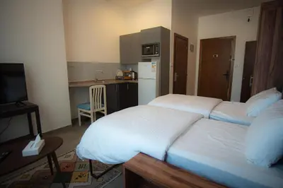 a bedroom with two beds and a small kitchen at Weibdeh Heights Hotel Suites in Amman