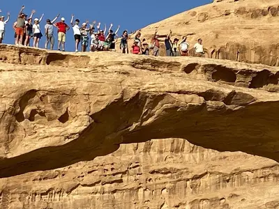 a group of people standing on top of a cliff at Rum desert camp in Wadi Rum