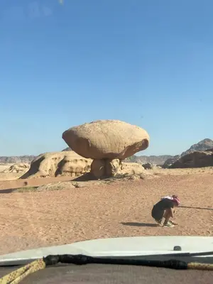 a person in the desert with a large rock at Bedouin Desert Cave in Wadi Rum