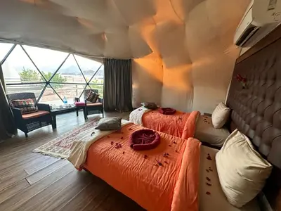 two beds in a room with a large window at Rum Awaad luxury camp in Wadi Rum