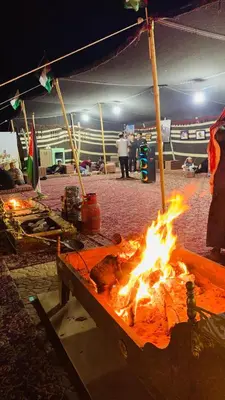 a fire in a pit with people standing around it at Rum Awaad luxury camp in Wadi Rum