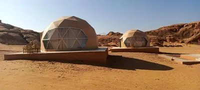 two domes in the desert with rocks in the background at Wadi Rum Aviva camp in Wadi Rum