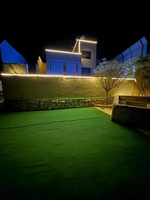 a house lit up at night with a green lawn at Lionden jerash استراحة وشالي عرين الاسد جرش in Jerash