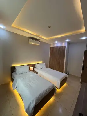 two beds in a hotel room with lights at 7 Days Hotel in Umm Uthainah
