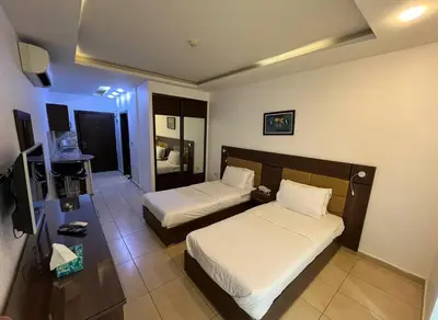 a hotel room with two beds and a television at 7 Days Hotel in Umm Uthainah