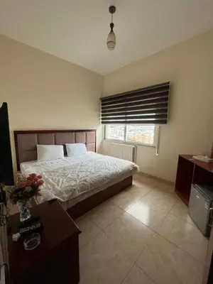 a bedroom with a bed and a table and a window at Nojoom Hotel in Amman