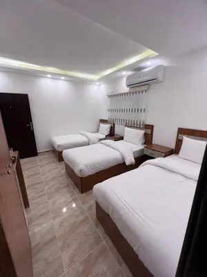 a hotel room with three beds with white sheets at Petra Family Hotel in Wadi Musa