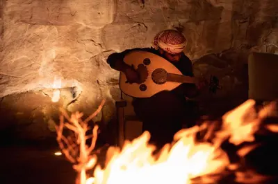 a man holding a guitar over a fire at The Villas - Bedouin Boutique Resort in Wadi Rum