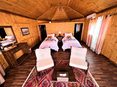 a bedroom with two beds in a wooden house at The Villas - Bedouin Boutique Resort in Wadi Rum