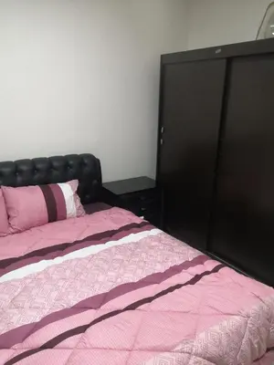 a bed with a black headboard and a pink blanket at Al-Shokhaibie 51 Building- Soufan Studios in Ţāb Kirā‘