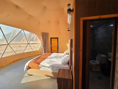 a bedroom with a bed in a room with a window at Scarlet Luxury Camp Wadi Rum in Wadi Rum