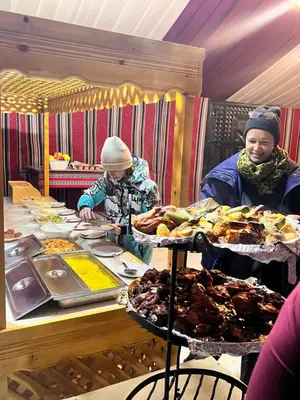 two people standing at a buffet table with food at Scarlet Luxury Camp Wadi Rum in Wadi Rum