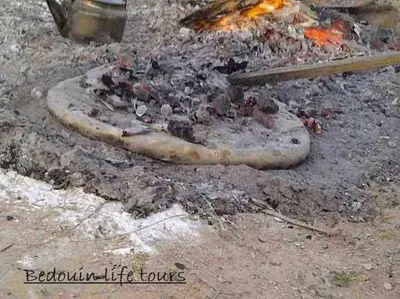 a pizza being cooked on a grill with fire at Cozy House in Wadi Musa