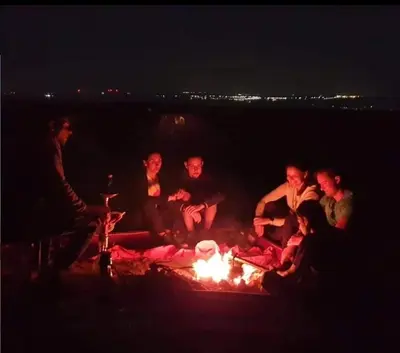 a group of people sitting around a fire at night at Dana Sunset Eco Camp in Dana
