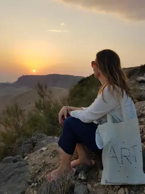 a woman sitting on a rock watching the sunset at Dana Sunset Eco Camp in Dana