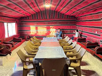 a long table and chairs in a room with red walls at Dana Sunset Eco Camp in Dana