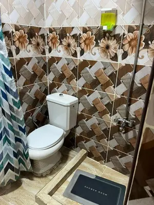 a bathroom with a toilet and a tiled wall at Petra Main Gate Studios in Wadi Musa