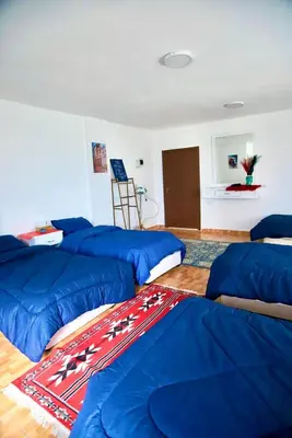 a room with four blue beds and a rug at Petra Main Gate Studios in Wadi Musa