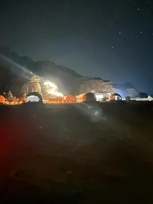 a night view of a mountain with lights on at Nara Wadi RUM Camp in Wadi Rum
