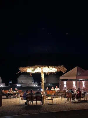 a group of people sitting under an umbrella at night at Rum Kingdom Camp in Wadi Rum