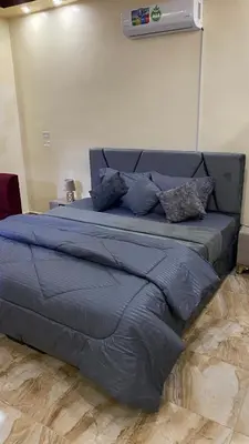 a large bed with blue sheets and pillows on it at Petra Rose Apartment in Wadi Musa
