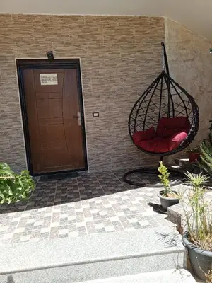a red pillow in a swing hanging from a wall at Petra Rose Apartment in Wadi Musa