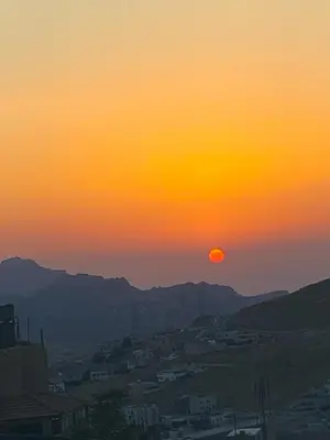 a sunset with the sun setting over a city at Petra Rose Apartment in Wadi Musa