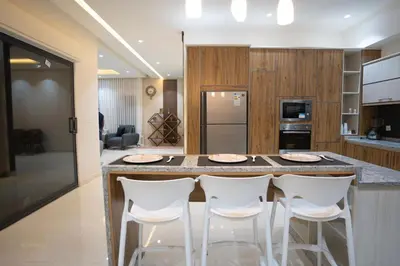 a kitchen with a large island with white bar stools at مزرعة وفيلا الريان وادي رم in Ruʼaysat al Khālidī