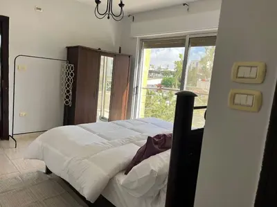 a bedroom with a large bed with a large window at Ronza Elegant Apartment in Amman