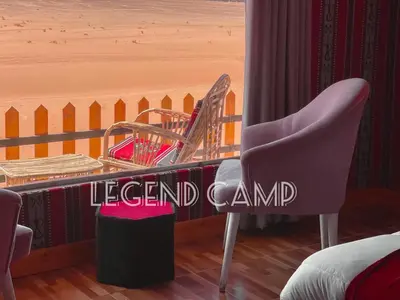 a bedroom with a bed and a table and a chair at Wadi Rum Alia Luxury Camp in Wadi Rum