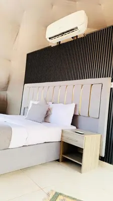 a bedroom with a large bed and a night stand at Wadi Rum Alia Luxury Camp in Wadi Rum