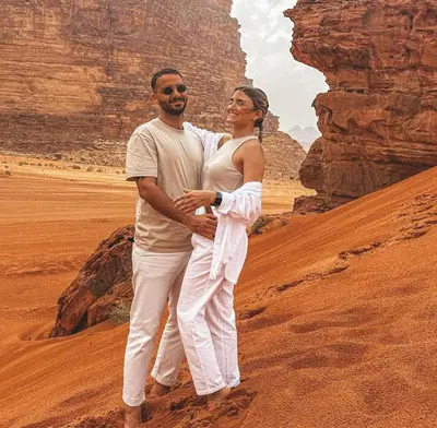 a man and a woman standing in the desert at Wadi Rum Alia Luxury Camp in Wadi Rum