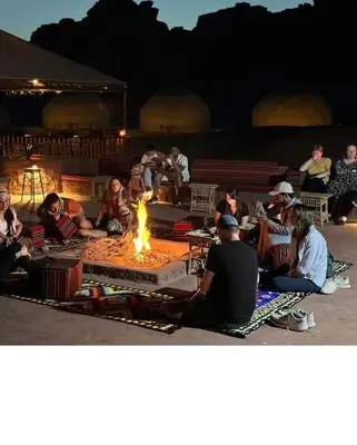 a group of people sitting around a fire at Wadi Rum Alia Luxury Camp in Wadi Rum