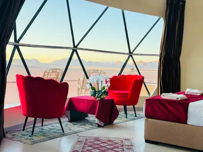 a room with red chairs and a large window at Wadi Rum Alia Luxury Camp in Wadi Rum
