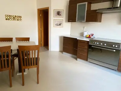 a kitchen with a stove and a table and chairs at Contemporary Semi Villa Apartment with Private Entrance in Khalda in Amman