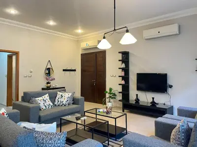 a living room with two couches and a tv at Contemporary Semi Villa Apartment with Private Entrance in Khalda in Amman