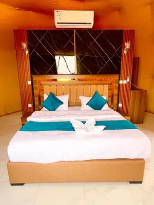a bedroom with a large bed with blue and white pillows at Anwar Al Qamar Luxury Hotel in Wadi Rum