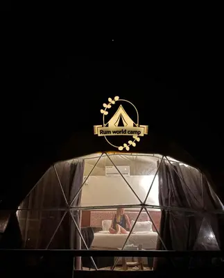 a woman sitting on a couch in a glass dome at RUM WORLD BUBBLE lUXURY CAMP in Wadi Rum